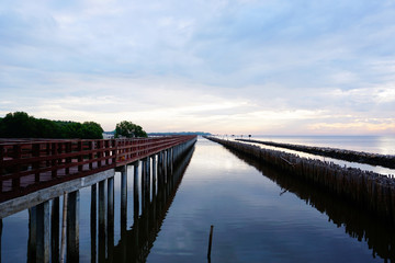 Fototapeta na wymiar Long simple wooden jetty leading into blue ocean in the gulf of Thailand with sunrise