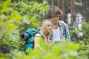 Hiking couple reading map together in forest
