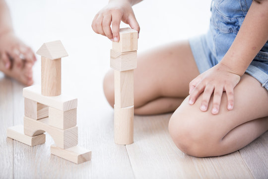 Midsection of girl playing with building blocks on hardwood floor