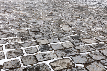 pattern of gray cobblestone city sidewalk covered with snow
