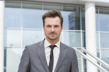 Portrait of confident young businessman standing outside office building