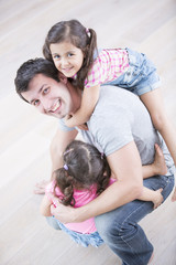 High angle portrait of playful father carrying girls at home