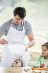 Smiling father preparing sandwich with daughters at home
