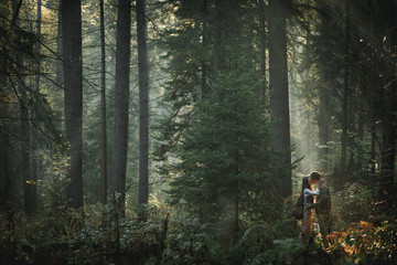 Beautiful young couple kiss outdoors in the forest, true love an