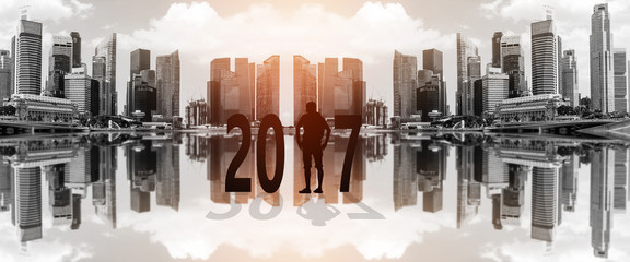 Silhouette of young man standing between 2017 years with beautiful blurred city background.