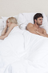 Fototapeta na wymiar Angry young couple avoiding each other in bed