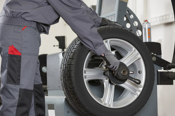 Midsection of male mechanic repairing car's wheel in repair shop