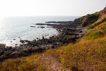 Fototapeta na wymiar Waves break on the rocky beaches of Arambol in India.