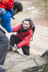 Hiker helping friend while trekking in forest