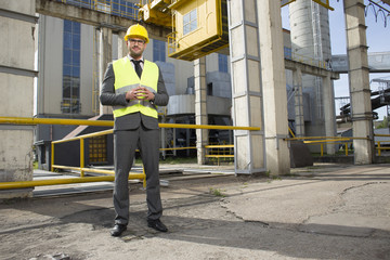 Full length portrait of confident young male architect standing outside industry