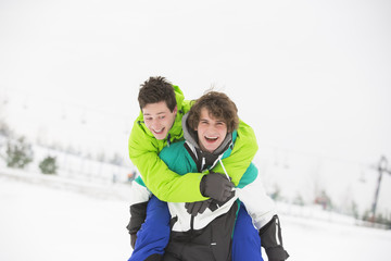 Young male friends enjoying piggyback ride in snow