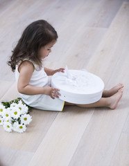 Full length side of little girl opening gift box on floor at home
