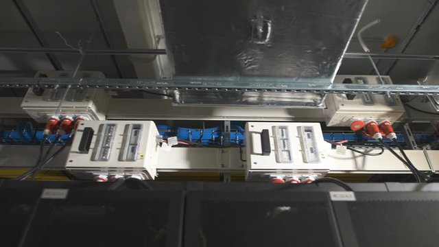 Several electric power units are equipped with a switch inside, attached under the ceiling in the industrial premises of IT companies. Devices connected to a common supply by cables with red plug.