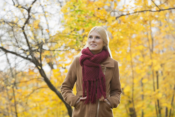 Thoughtful woman in jacket looking away at park during autumn
