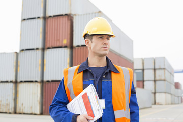 Mid adult man with clipboard in shipping yard