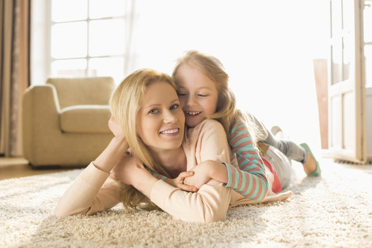 Portrait of happy mother with daughter lying on floor at home