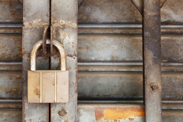 Dirty padlock on rusty steel shutter door