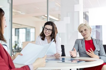 Mature businesswoman discussing with female colleagues at table in office