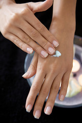 Fototapeta premium Close-up of woman rubbing lotion on hands