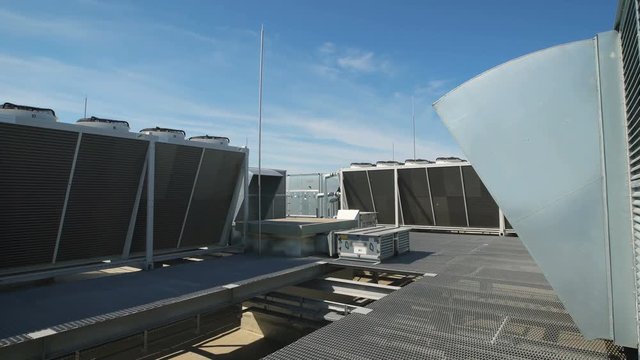 Large ventilation system installed on the roof of an industrial building. Purification of indoor air with the help of external equipment. Beautiful blue sky on the background.