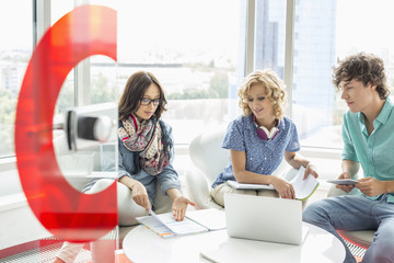 Businesspeople discussing over file in creative office
