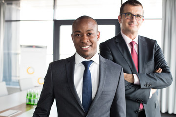 Portrait of confident businessman with male colleague in office