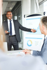 Smiling young businessman giving presentation in board room