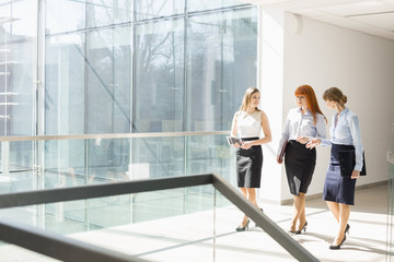 Full-length of businesswomen walking at office hallway
