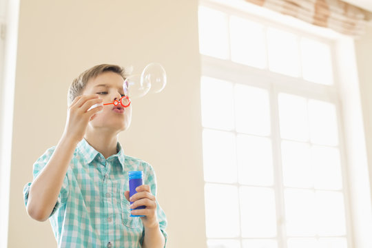 Boy blowing bubbles at home
