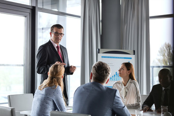 Mature businessman having discussion with colleagues in board room