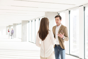 Young businessman discussing with female colleague in new office