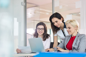 Team of businesswomen using laptop at table in office
