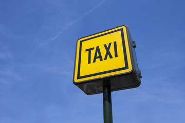 Low angle view of taxi sign against blue sky