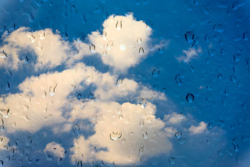 Drops of water on glass window over blue sky.