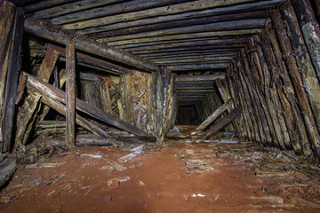 Fototapeta na wymiar Undreground abandodned mine tunnel shaft with wooden mounting frame lining