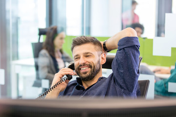 Smiling mid adult businessman talking on telephone in office