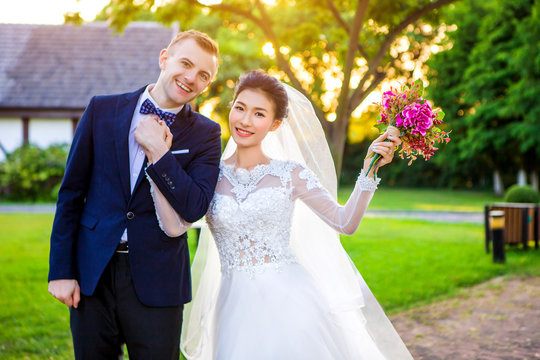 Portrait of happy wedding couple holding hands while standing at lawn
