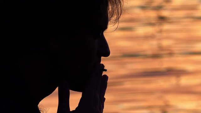 man smoking with water at the sunset  in background