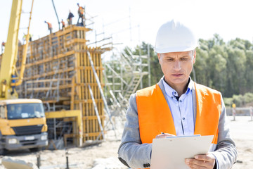 Supervisor writing on clipboard at construction site