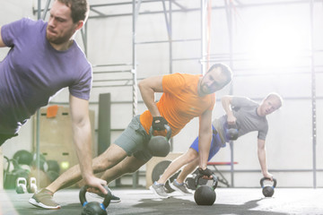 Naklejka na ściany i meble Men exercising with kettlebells in crossfit gym