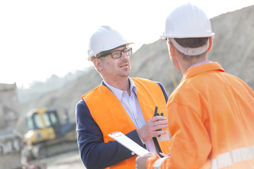Architects discussing at construction site on sunny day