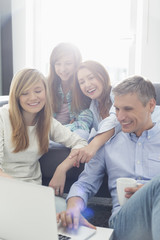 Happy parents with daughters using laptop in living room