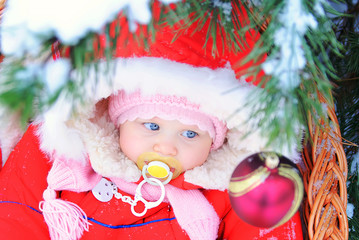 Little girl in sitting in a sled in the winter under the tree 