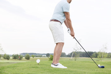 Obraz premium Low section side view of man playing golf against clear sky