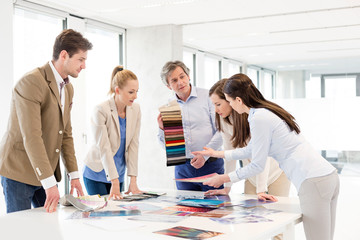 Team of design professionals with swatches having discussion at table in new office