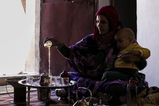 Saharawi woman preparing tea with her baby, Tindouf, Algeria