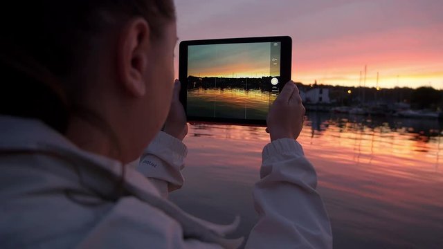 making photo with a tablet at the sunset near the river