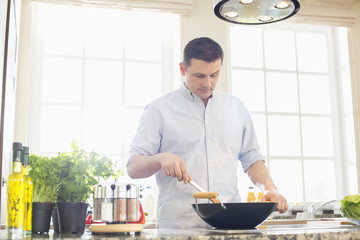 Middle-aged man preparing food in kitchen