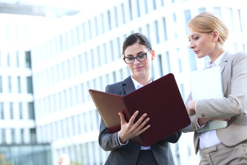 Businesswomen reading folder while standing outside office building