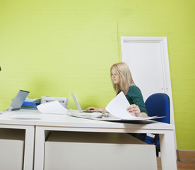 Woman working in office against green wall